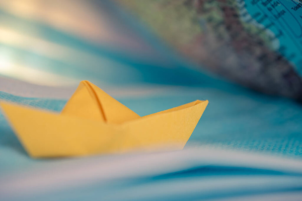 жовтий орігамі човен, що пливе на синьому морі з хірургічними масками.
. - Фото, зображення