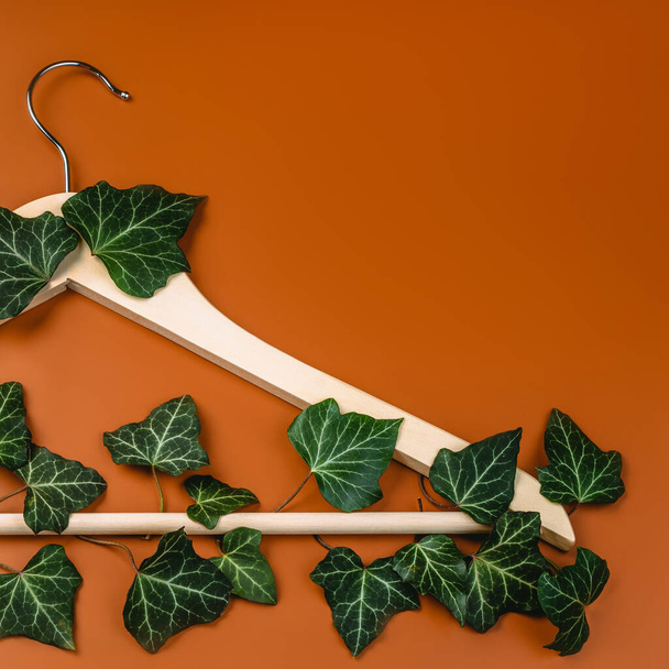 Hangers entwined with plants on background with copy space.Conscious and environmentally friendly consupmtion in shopping.Recycling or zero waste concept.Shopping,sale,promo. - Photo, Image