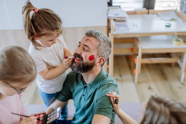 Three little girls putting on make up on their father, fathers day with daughters at home. - Φωτογραφία, εικόνα