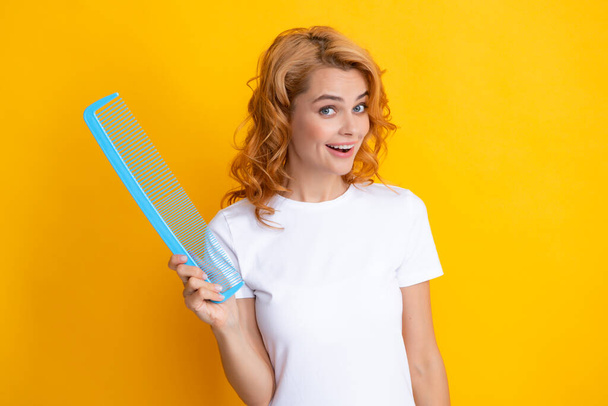 Redhead woman with a comb, isolated on yellow background. - Photo, Image