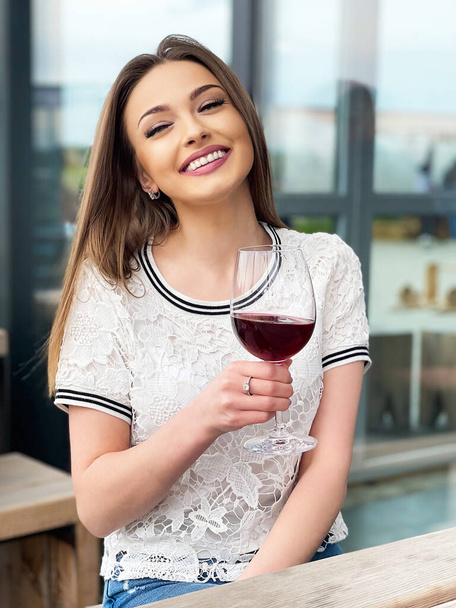 Молода жінка тримає келих червоного вина
 - Фото, зображення