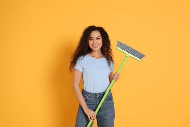 African American woman with green broom on orange background - Foto, Imagem