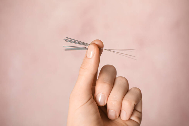 Woman holding needles for acupuncture on pink background, closeup - Foto, Imagen