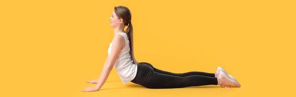 Sporty young woman training against yellow background - Fotó, kép