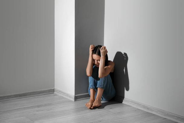 若い女性が家で床に座って泣いている。暴力的概念 - 写真・画像