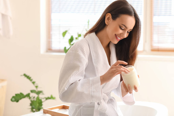 Young woman with jar of coconut oil in bathroom - Photo, image