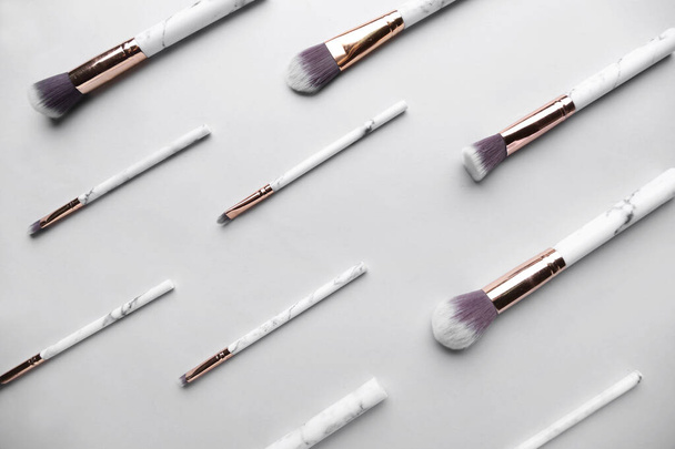 Set of marble makeup brushes on light background - Фото, изображение