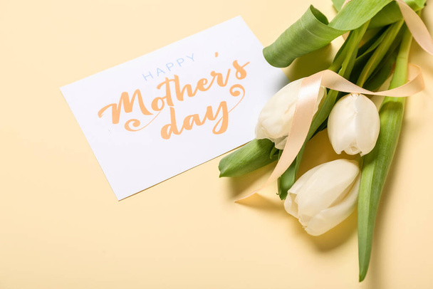 Card with text HAPPY MOTHER'S DAY, white tulips and ribbon on beige background - Foto, imagen