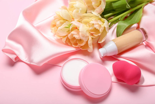 Boeket tulpen, decoratieve cosmetica en make-up spons op roze achtergrond - Foto, afbeelding
