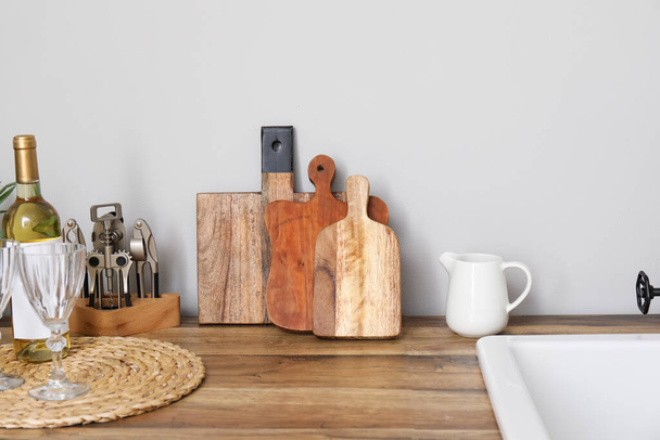 Cutting boards with kitchen utensils on counter near light wall - Photo, Image