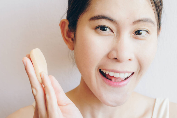 Portrait de bonheur femme asiatique après avoir appliqué la poudre de fond de teint bouffée sur son visage pour couvrir les défauts et changer la peau naturelle. Beauté et Cosmétique plan conceptuel. - Photo, image