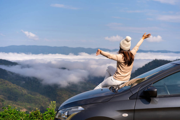 Young woman travelers with car watching a beautiful sea of fog over the mountain while travel driving road trip on vacation - Фото, изображение