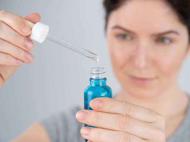 Caucasian woman uses blue anti-wrinkle face serum. - Фото, изображение