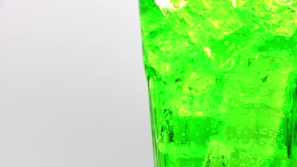 Groen sprankelend water met ijs in glas. Groen sprankelend water drinken over witte achtergrond. - Video