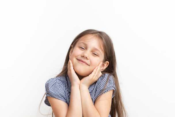 Nettes 7-jähriges Mädchen lächelt und hält die Hände auf dem Gesicht. - Foto, Bild