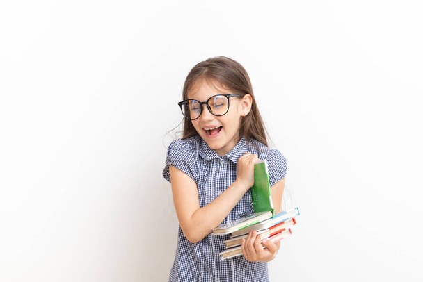 Bonito menina de 7 anos com óculos sorrindo segurando livros em suas mãos - Foto, Imagem