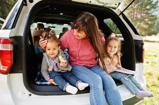 Family at vehicle interior. Mother with her daughters. Children in trunk. Traveling by car in the mountains, atmosphere concept. - Фото, изображение