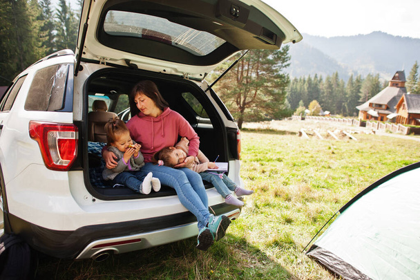 Family at vehicle interior. Mother with her daughters. Children in trunk. Traveling by car in the mountains, atmosphere concept. - Photo, image