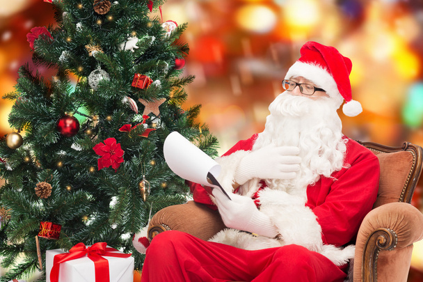 man in costume of santa claus with notepad - Foto, Bild