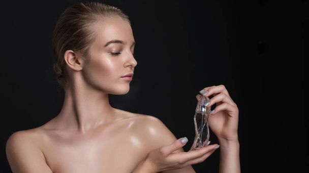Young beautiful woman with a bottle of perfume. Model with healthy skin, close up portrait. Cosmetology, beauty and spa - Fotoğraf, Görsel
