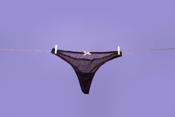 Thong black bikini panties, lace sexy underwear lingerie on rope isolated background. - 写真・画像