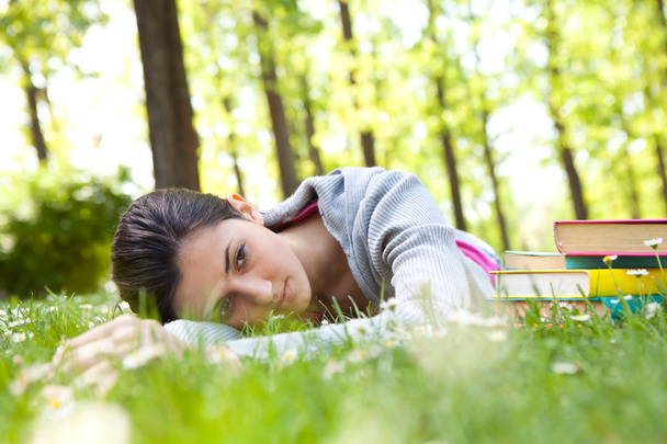 Tired student girl lying on grass - Fotoğraf, Görsel