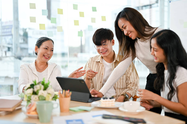 Concepto de trabajo en equipo, gente de negocios asiáticos trabajando juntos con felicidad, viendo algo divertido juntos en la reunión. - Foto, Imagen