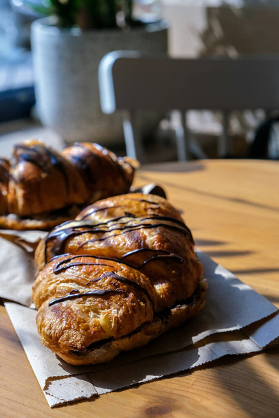 Fresh and tasty Croissants with chocolate butter and banana on crumpled paper. Breakfast at cafe. Morning routine. French pastry. Baked bun. Oven croissant. Sunlight street cafe. Lifestyle restaurant - Photo, Image