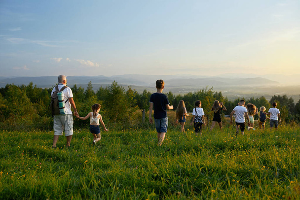 Niños con anciano avanzando en las colinas. - Foto, Imagen