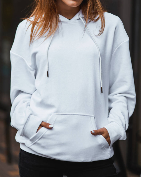 Modèle de conception pour le logo des vêtements. Une femme porte un sweat à capuche blanc dans la rue. - Photo, image
