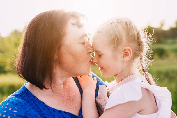 Großmutter hält Enkelin auf dem Arm und küsst Nase - Foto, Bild