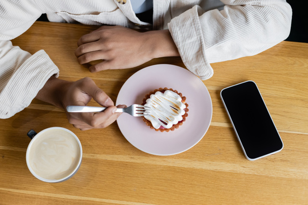 horní pohled na africký Američan drží vidličku v blízkosti chutné koláč a smartphone s prázdnou obrazovkou  - Fotografie, Obrázek