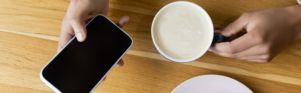 shora pohled na afrického Američana držícího smartphone a šálek cappuccino, banner - Fotografie, Obrázek