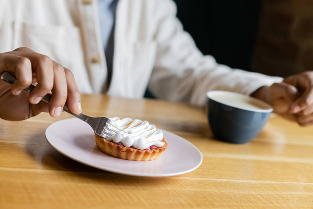 partial view of african american man holding fork near tasty tart and cup of coffee  - Photo, Image