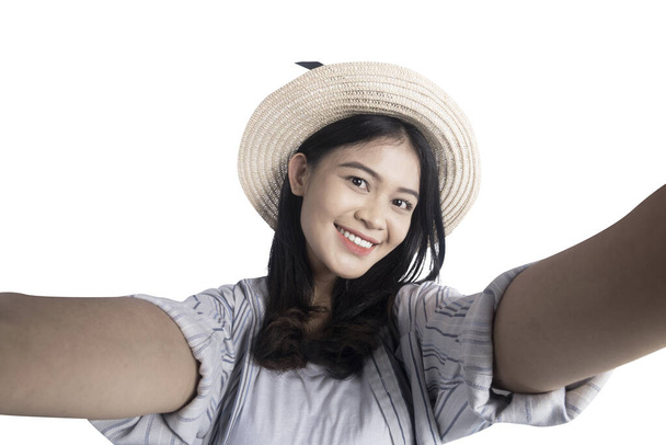 Asian woman with a hat taking a self-portrait isolated over white background - Foto, Imagen