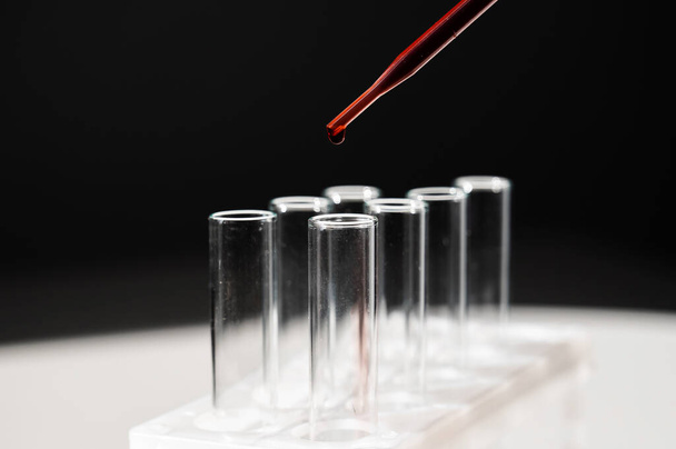 Close-up of a laboratory assistant dripping blood from a pipette into a test tube.  - Foto, Bild