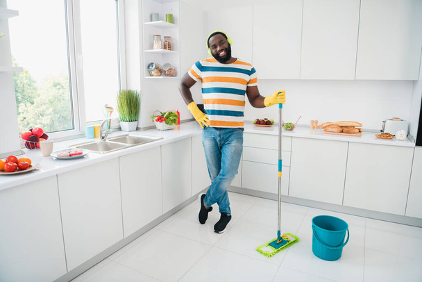 Full body portrait of cheerful funny person hold mop enjoy wireless mo3 sound standing kitchen room house indoors - Foto, imagen