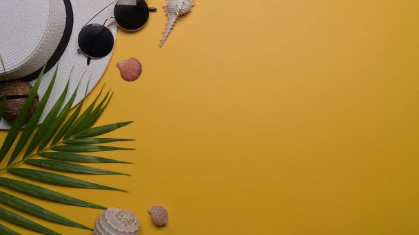 Reiseaccessoires, Muscheln und tropische Palmenblätter auf gelbem Hintergrund mit Kopierraum. Reise, Sommer und Urlaubskonzept. - Foto, Bild