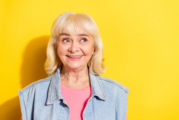 Photo of charming sweet lady pensioner dressed denim waistcoat looking empty space isolated yellow color background - 写真・画像