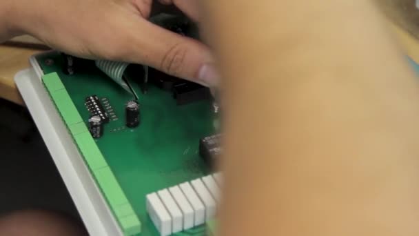 Az ember áramkört javít a számítógéphez műhelyben. A mester keze csavarhúzóval szorítja meg a reteszt. Az alaplap szétszerelése diagnosztikai célra extrém közelkép - Felvétel, videó