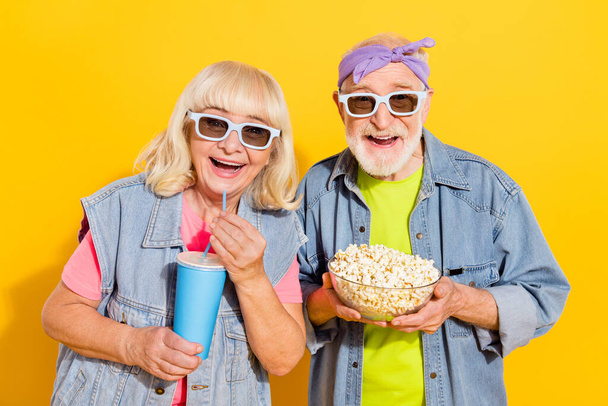 Foto do marido impressionado animado esposa usar camisas jeans assistindo filme de comédia isolado cor amarela fundo - Foto, Imagem