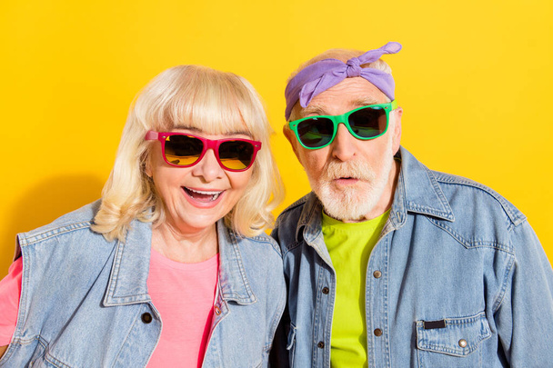 Portrait of attractive cheerful grey-haired couple wearing funny clothes good mood isolated over bright yellow color background - Фото, изображение
