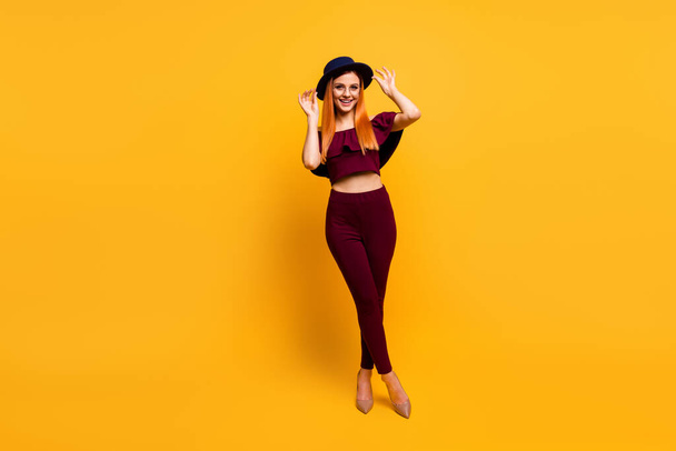 Full length photo of adorable charming lady dressed red clothes spectacles headwear walking empty space isolated yellow color background - Zdjęcie, obraz