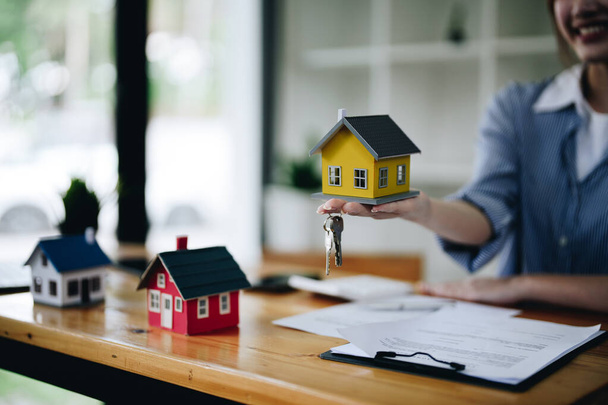 Агент по недвижимости выдает ключи и модель дома, концепция ипотеки на покупку жилья. - Фото, изображение