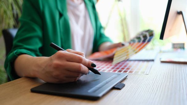 Designér kreslí náčrty na grafický tablet a drží paletu barev - Fotografie, Obrázek