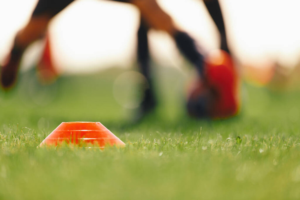 Football Grass Training Field. Soccer Equipment on Grass Pitch. Red Soccer Training Marker. Running Player in the Background - Fotoğraf, Görsel