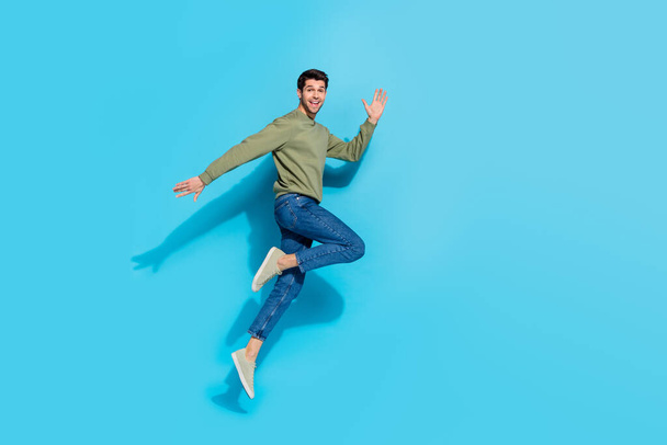 Ganzes Foto von flippigen Millennial Brunet Kerl laufen tragen Hemd Jeans Turnschuhe isoliert auf blauem Hintergrund - Foto, Bild