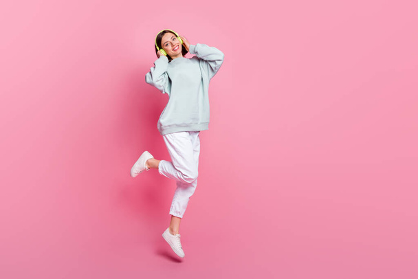 Full size photo of sweet bob hairstyle millennial lady jump wear headphones hoodie pants shoes isolated on pink background - Photo, image