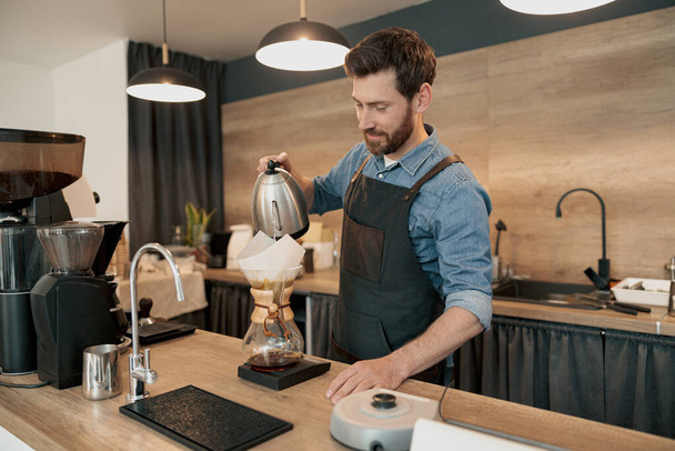 Homme barista portant tablier faisant café filtre à la cafétéria - Photo, image