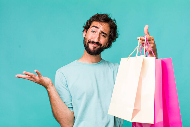 young adult hispanic crazy man. shopping bags concept - Фото, изображение